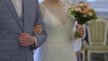 Gelin ve damat düğün töreninde ayakta duruyor. Aşık erkek ve kadın el ele tutuşuyorlar..