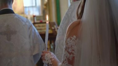 Düğün töreninde gelin ve damat ellerinde mumlarla kilisede. Hıristiyanlık ya da Katoliklik, Tanrı 'ya inanç. Kilise ayini. Rahip ödüyor..