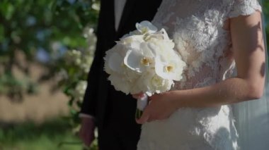 Gelin ve damat açık hava düğün töreninde duruyor. Aşık erkek ve kadın el ele tutuşuyorlar..