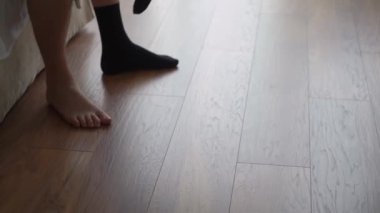 Siyah çorap giyen biri. Adam yatakta oturuyor ve giyiniyor. Tanımlanamayan erkek ve bacakları.