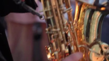 Görüntü bir saksafoncunun altın bir saksafoncunun elini gösteriyor, bir caz performansının canlı özünü yakalıyor.