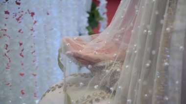 Bu çarpıcı yakın plan, akmakta olan bir peçenin yanında incilerle süslenmiş bir gelin eli yakalıyor.