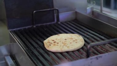 Mükemmel bir yassı ekmek şu anda ticari bir ızgarada pişiriliyor, geleneksel ızgara tekniklerinin sanatını gözler önüne seriyor. Bu da herkesin keyif alması için lezzetli ve enfes sonuçlara yol açıyor.