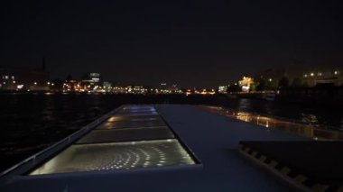 Büyüleyici huzurlu bir gece teknesi gezisi şehrin ışıklarını ve sudaki yansımalarını güzel bir şekilde sergiliyor.