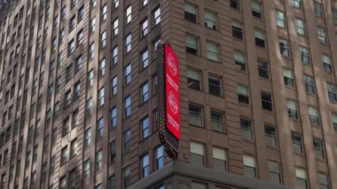 NEW YORK, ABD - 10 Nisan 2024: Parlak bir şehir köşesinde, çağdaş bir bina gökyüzünü renkli ışıklarla zenginleştiren canlı reklamlar sunan bir LED reklam panosunu gururla sergiliyor