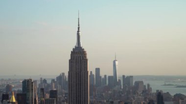 Nefes kesen panoramik manzara ikonik New York şehrinin siluetini sergiliyor, Empire State Binası ve One World Trade Center gibi simgelerle güzel, berrak bir gökyüzüne karşı