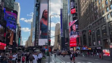NEW YORK, ABD - 15 AĞUSTOS 2024: Güneşli bir gökyüzü altında parıldayan sayısız insan ve canlı reklamlarla dolu hareketli bir Times Meydanı