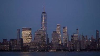 Bir Dünya Ticaret Merkezi 'nin zarif bir şekilde aydınlatıldığı ve parladığı alacakaranlıktaki New York siluetinin nefes kesici manzarası.