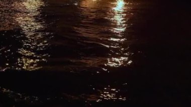 Sakin sular, yüzeyde hafifçe dans eden ılık, altın yansımaların altında hafifçe parıldıyor.