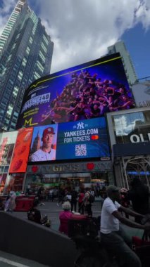 NEW YORK, ABD - 15 AĞUSTOS 2024: Güneşli bir gökyüzü altında parıldayan sayısız insan ve canlı reklamlarla dolu hareketli bir Times Meydanı