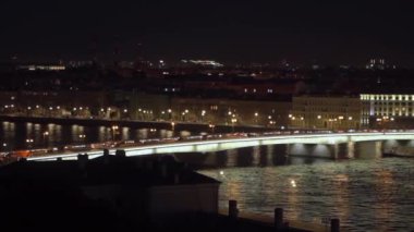 Saint-Petersburg 'da nehri zarifçe kaplayan parlak bir köprünün aydınlattığı canlı bir şehri gösteren nefes kesici bir gece manzarası.
