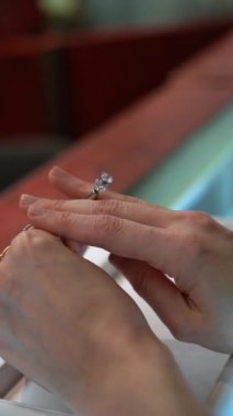 Zarif bir elmas yüzüğü tutan bir elin yakın çekimi, zarif ve çarpıcı tasarımı vurguluyor.