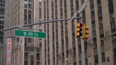 Canlı ve hareketli bir sokak sahnesi, belirgin bir trafik ışığı ve Manhattan 'ın göbeğinde yer alan W 49. Cadde tabelası, dinamik şehir manzarasını güzel bir şekilde gözler önüne seriyor.