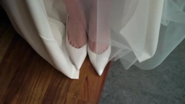 Yakından bakınca zarif gelinlik ayakkabıları ve göz kamaştırıcı bir gelinlik görünüyor.