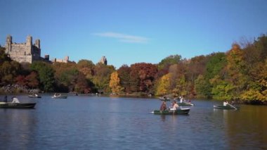 Renkli ağaçlar ve açık mavi gökyüzünün yer aldığı hareketli bir sonbahar parkında dingin ve pitoresk bir tekne sahnesi gözler önüne seriliyor. New York 'taki Central Park.