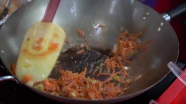 Kızarmış, canlı taze sebzelerle dolu bir tavanın yakından görüntüsü spatulayla ustalıkla karıştırılıyor.