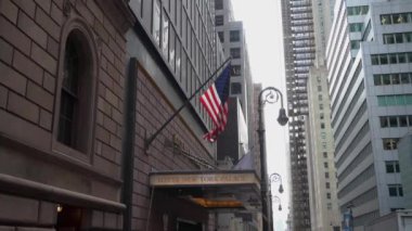 NEW YORK, ABD - 4 Nisan 2024: Bir Amerikan bayrağının gökdelenlerin arasında gururla dalgalandığı büyüleyici şehir manzarası. Lotte Oteli Girişi.