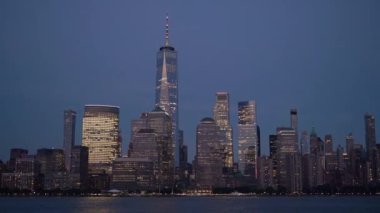 Bir Dünya Ticaret Merkezi 'nin zarif bir şekilde aydınlatıldığı ve parladığı alacakaranlıktaki New York siluetinin nefes kesici manzarası.