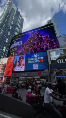 NEW YORK, ABD - 15 AĞUSTOS 2024: Güneşli bir gökyüzü altında parıldayan sayısız insan ve canlı reklamlarla dolu hareketli bir Times Meydanı