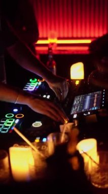 NEW YORK, ABD - 10 Şubat 2024: Bir DJ, loş bir gece kulübünde parlak ışıklarla aydınlatılmış profesyonel bir DJ konsolunda ustaca müziği karıştırıyor. Neon ışıkları ve dijital görüntüler