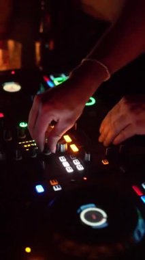 NEW YORK, ABD - 22 Ocak 2024: Canlı bir gece kulübünde canlı bir DJ 'in pikaplarda müzik karıştırırken yakın plan görüntüleri. DJ 'in elleri çeşitli kontrolleri ayarlıyor ve bir...