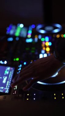 NEW YORK, ABD - 22 Ocak 2024: Bir DJ, loş bir gece kulübünde parlak ışıklarla aydınlatılmış profesyonel bir DJ konsolunda ustaca müziği karıştırır. Neon ışıkları ve dijital ekranlar dinamik bir görüntü oluşturur