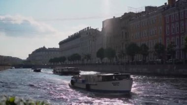 SAINT-PETERSBURG, RUSSIA - 2 Temmuz 2024: Sakin bir nehirde yüzen renkli teknelerin çarpıcı görüntüsü, tarihi binalar ve güzel manzaralarla çevrili