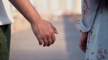 Birbirine sarılmış iki el birbirine uzanıyor, derin bağlantıyı simgeliyor ve güneşli bir köprüde derin aşkı simgeliyor.