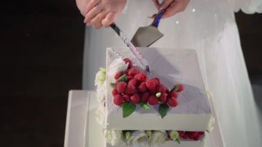 Yeni evlilerin, gelin ve damadın düğünleri sırasında romantik bir pasta yapma deneyimini paylaştıkları güzel bir an. Çiçek ve böğürtlenli beyaz pasta aşkı ve birliği simgeler.