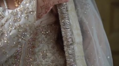 Güzel süslenmiş bir elbisenin yakın plan görüntüsü. Narin bir peçenin yanında karmaşık boncuk işçiliği de var.