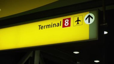 Bir havaalanındaki 8. terminale giden yolculara çok görünür olması için tasarlanmış iyi aydınlatılmış yön işareti.