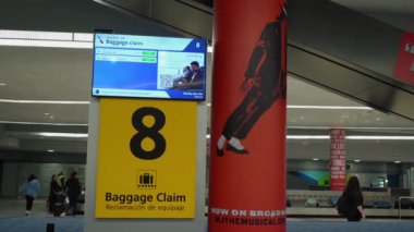 NEW YORK, ABD - 19 Mayıs 2024: Geniş havaalanı bagaj teslim alanı, çeşitli dijital işaret levhalarıyla birlikte boş bir bagaj kemerine sahiptir