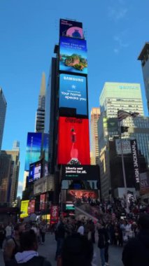 NEW YORK, ABD - 15 AĞUSTOS 2024: Güneşli bir gökyüzü altında parıldayan sayısız insan ve canlı reklamlarla dolu hareketli bir Times Meydanı