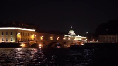 Saint-Petersburg 'daki tarihi bir binanın çarpıcı manzarası gece vakti suyla yansıyan yumuşak ışıklarla aydınlanıyor..