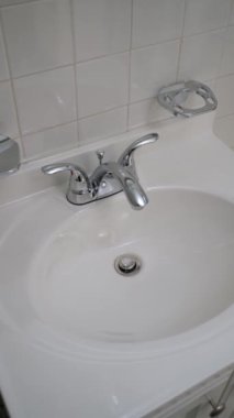 Temiz ve el değmemiş bir ortamda parlak krom bir musluk barındıran şık bir banyo lavabosu.