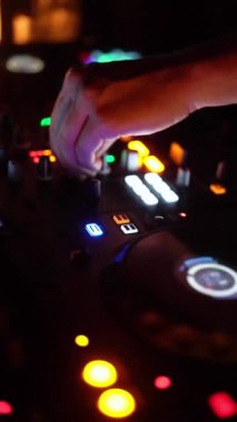 NEW YORK, ABD - 10 Şubat 2024: Bir DJ, loş bir gece kulübünde parlak ışıklarla aydınlatılmış profesyonel bir DJ konsolunda ustaca müziği karıştırıyor. Neon ışıkları ve dijital görüntüler