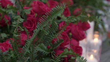 Parlak kırmızı güllerin ve yumuşak yanan mumların olduğu güzel bir sahne, büyüleyici romantik ortamlar için mükemmel.