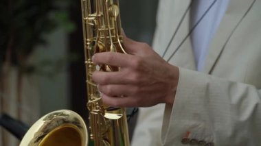 Yetenekli bir müzisyen, herkesin görmesi için şık bir takım elbise giyerken dikkat çekici bir saksafon yeteneği sergiler.