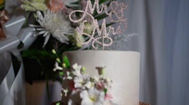 Bu çarpıcı düğün pastasında zarif bir Bay ve Bayan Topper ve güzel düzenlenmiş çiçekler var. Özel gününüzde aşkı ve birlikteliği kutlamak için mükemmel bir süs.