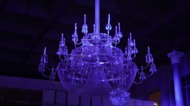 Mor ışıklarla aydınlatılan lüks bir kristal avize modern bir iç mekâna sofistike bir hava katar. Bu lüks armatürün ihtişamı atmosferi güçlendiriyor.