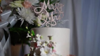 Bu çarpıcı düğün pastasında zarif bir Bay ve Bayan Topper ve güzel düzenlenmiş çiçekler var. Özel gününüzde aşkı ve birlikteliği kutlamak için mükemmel bir süs.