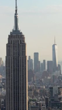 Nefes kesen panoramik manzara ikonik New York şehrinin siluetini sergiliyor, Empire State Binası ve One World Trade Center gibi simgelerle güzel, berrak bir gökyüzüne karşı