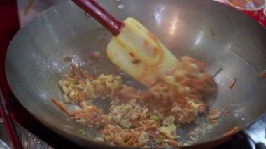 Kızarmış, canlı taze sebzelerle dolu bir tavanın yakından görüntüsü spatulayla ustalıkla karıştırılıyor.