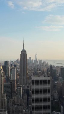 Nefes kesen panoramik manzara ikonik New York şehrinin siluetini sergiliyor, Empire State Binası ve One World Trade Center gibi simgelerle güzel, berrak bir gökyüzüne karşı