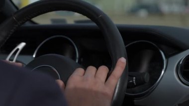 Araba kullanırken direksiyona tutunan, otomotiv kontrolünün özünü yakalayan ellere odaklanmış bir bakış..