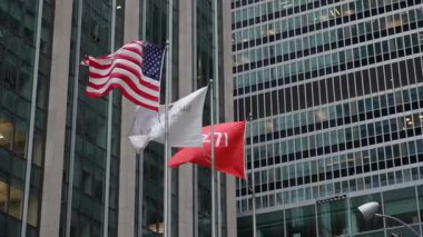 NEW YORK, ABD - 10 HAZİRAN 2025: Amerikan bayrakları ve kurumsal bayraklar şehirdeki parlak, modern cam bir binanın önünde nazikçe dalgalanıyor