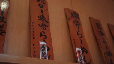 Güzel ahşap tabelalar otantik bir Japon restoranında çeşitli lezzetli ramen yemekleri sergiliyor.