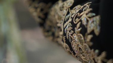 Zengin siyah kumaş, zarif sanatsal tasarım detaylarını gözler önüne seren karmaşık altın işlemeli bir fotoğraf.