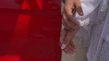 El ele tutuşan bir çiftin yakın çekimi, canlı kırmızı bir arka plana karşı sevgi ve bağlantı sergiliyor..