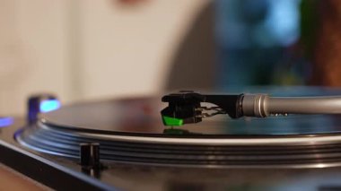 Stylus ile donatılmış, rahat bir ortamda vinil plak çalan bir turntable kolunun ayrıntılı görüntüsü.